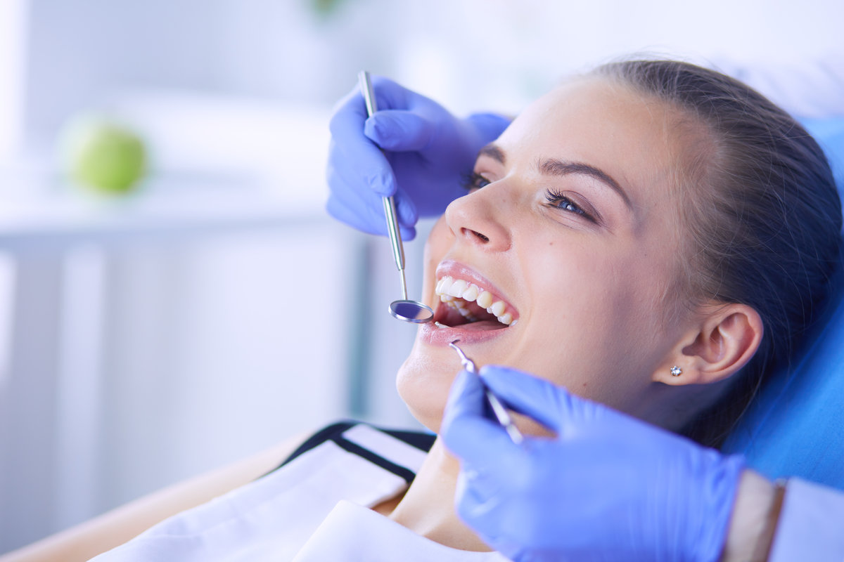 Young Female patient with open mouth examining dental inspection at dentist office