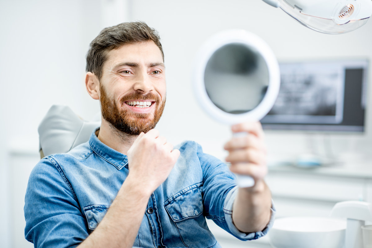Portrait of a handsome bearded man with healthy smile in the dental office