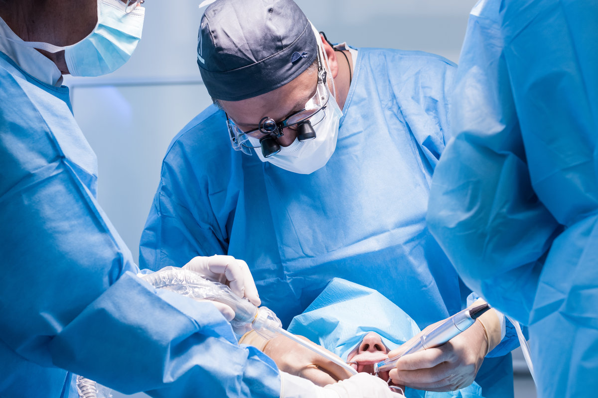A male dentist in uniform perform dental implantation operation