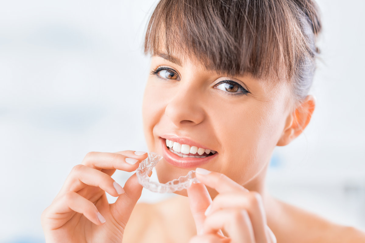 Woman wearing orthodontic silicone trainer. Invisible braces aligner. Mobile orthodontic appliance for dental correction.