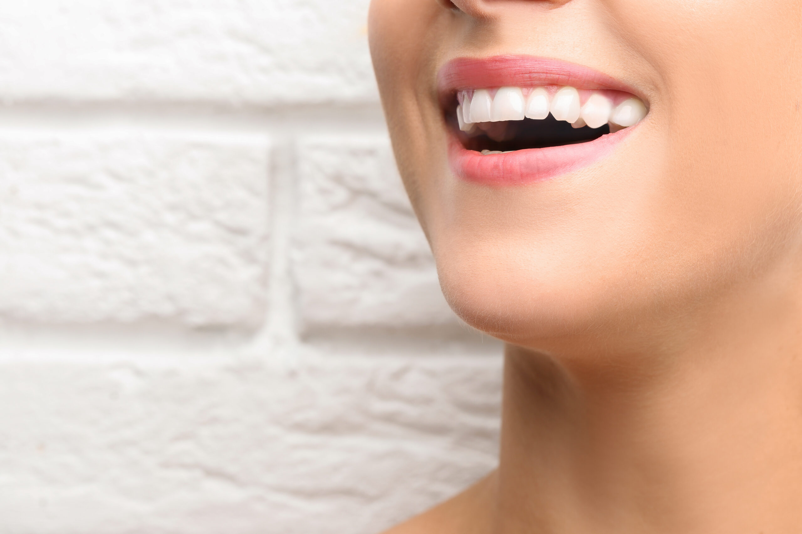 Young beautiful woman with healthy teeth smiling on light background