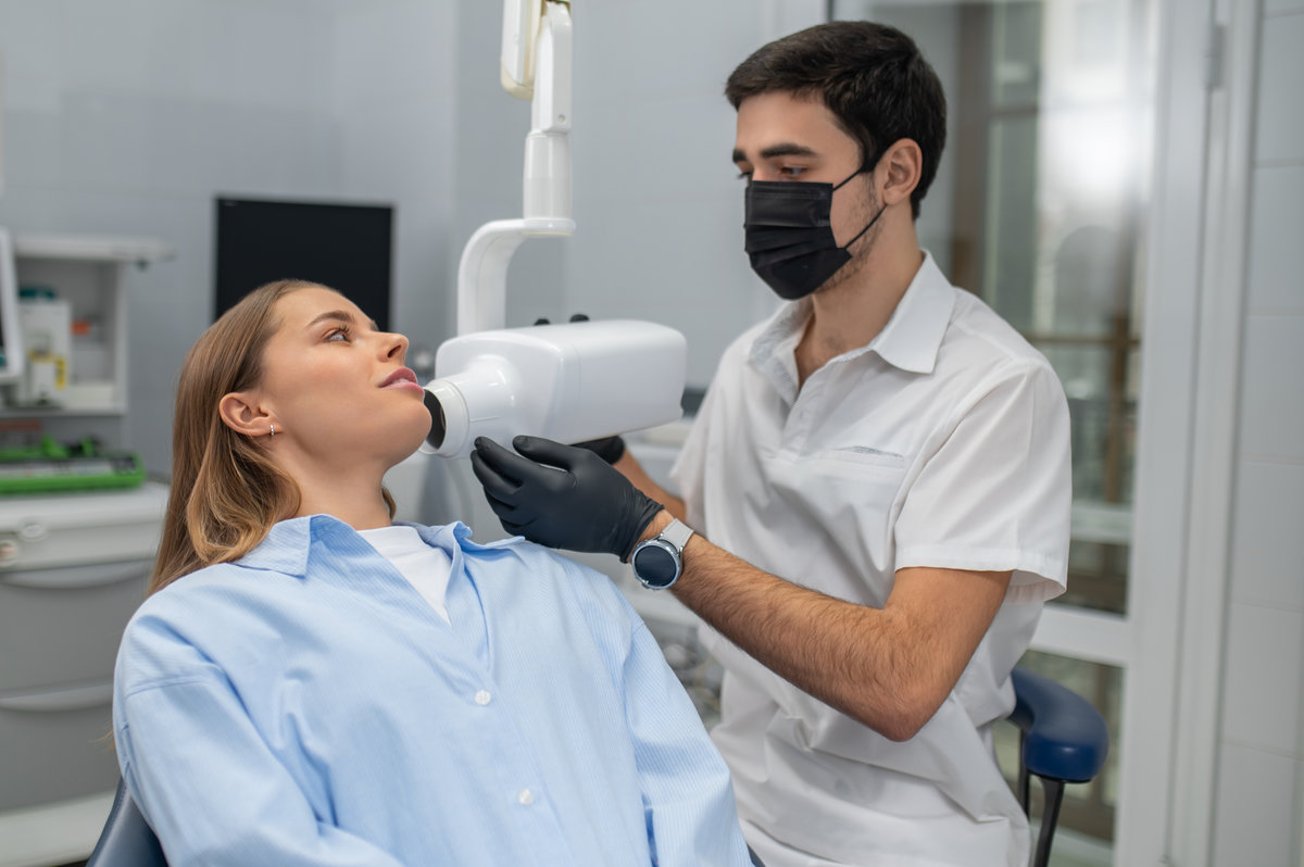 Dentist holding digital x-ray sensor near patient teeth for diagnostic in clinic
