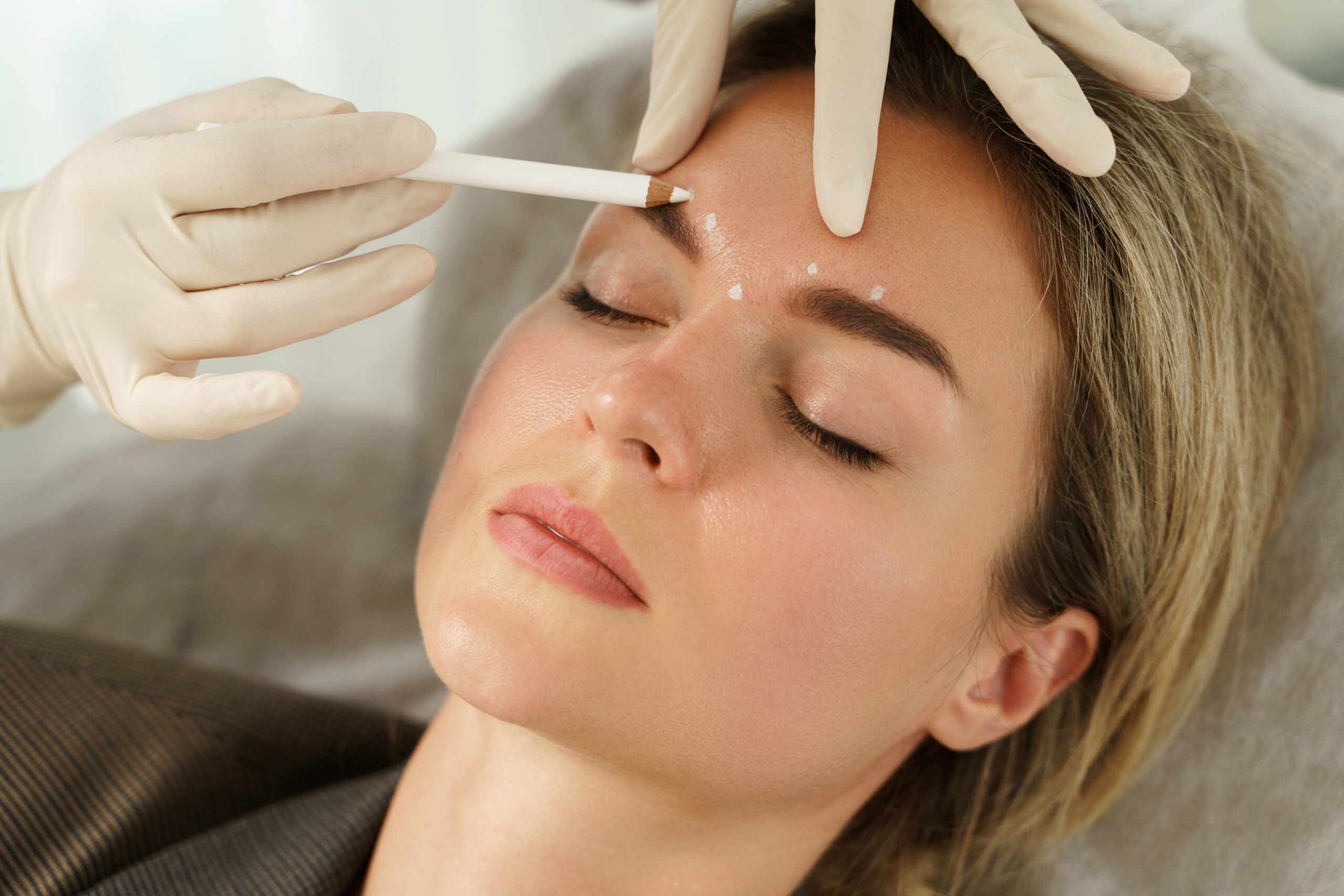 Doctor making marks on client's face before filler injections in aesthetics medical clinic